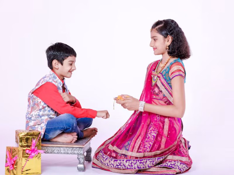 Sister tying rakhi with a greeting card in hand